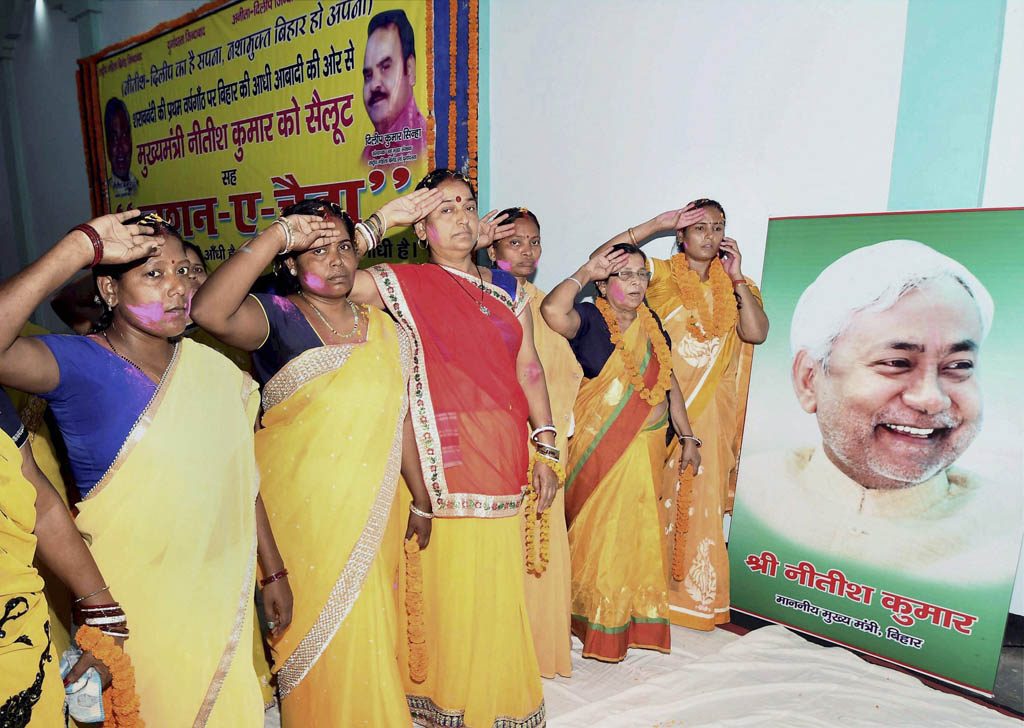 Patna: Rashtriya Mahila Brigade workers salute in front of Bihar Chief Minister Nitish Kumar's portrait on the completion of one year of the liquor ban in the state, in Patna on Thursday. PTI Photo(PTI4_6_2017_000126B)